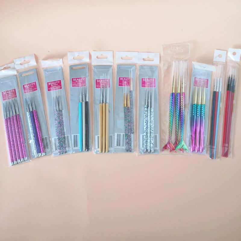 Close-up of a hand selecting a brush for nail design with various nail design paint brushes in the background