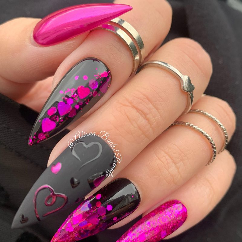 Close-up of hands applying black nail polish with detailed Valentine’s Day nail art