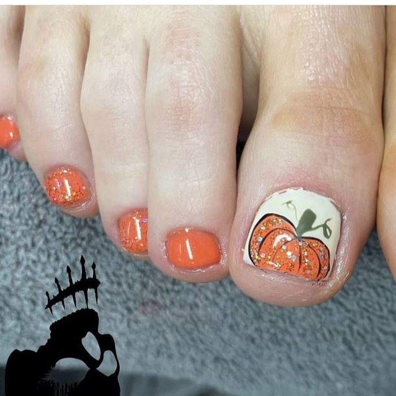 close-up of toes with warm fall pumpkin toe nail design