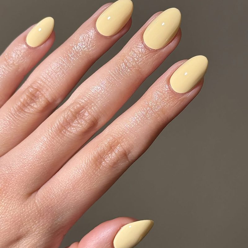 nails painted in yellow and white with simple sun nail design accents