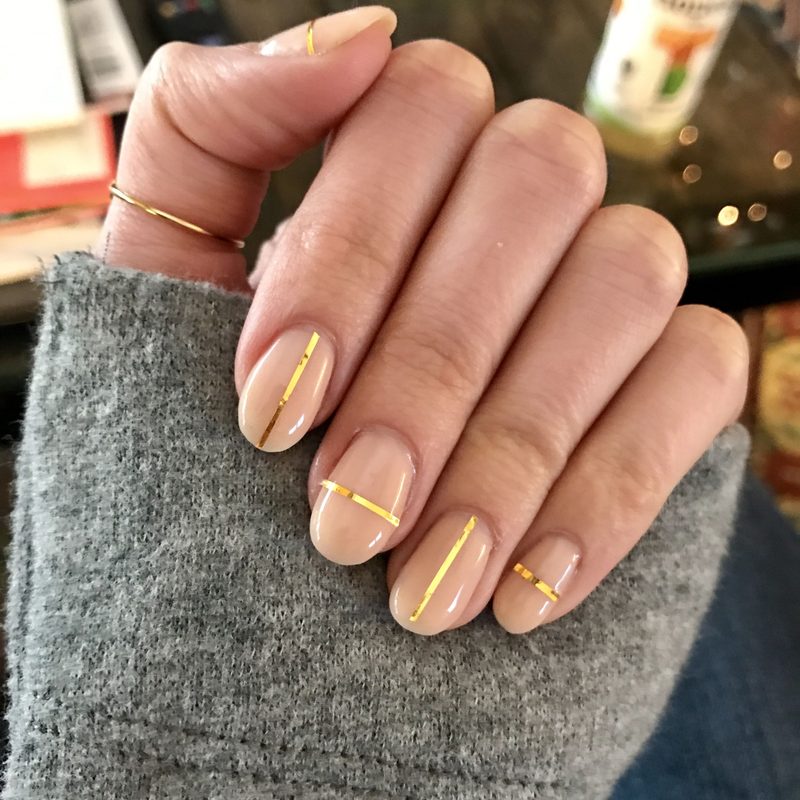 step-by-step image showing a hand painting a simple sun design on nails