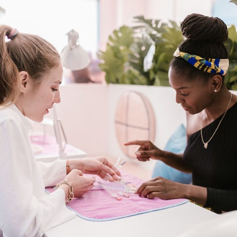 Nail technician consulting with a client using nail design wheel generator for nail art inspiration